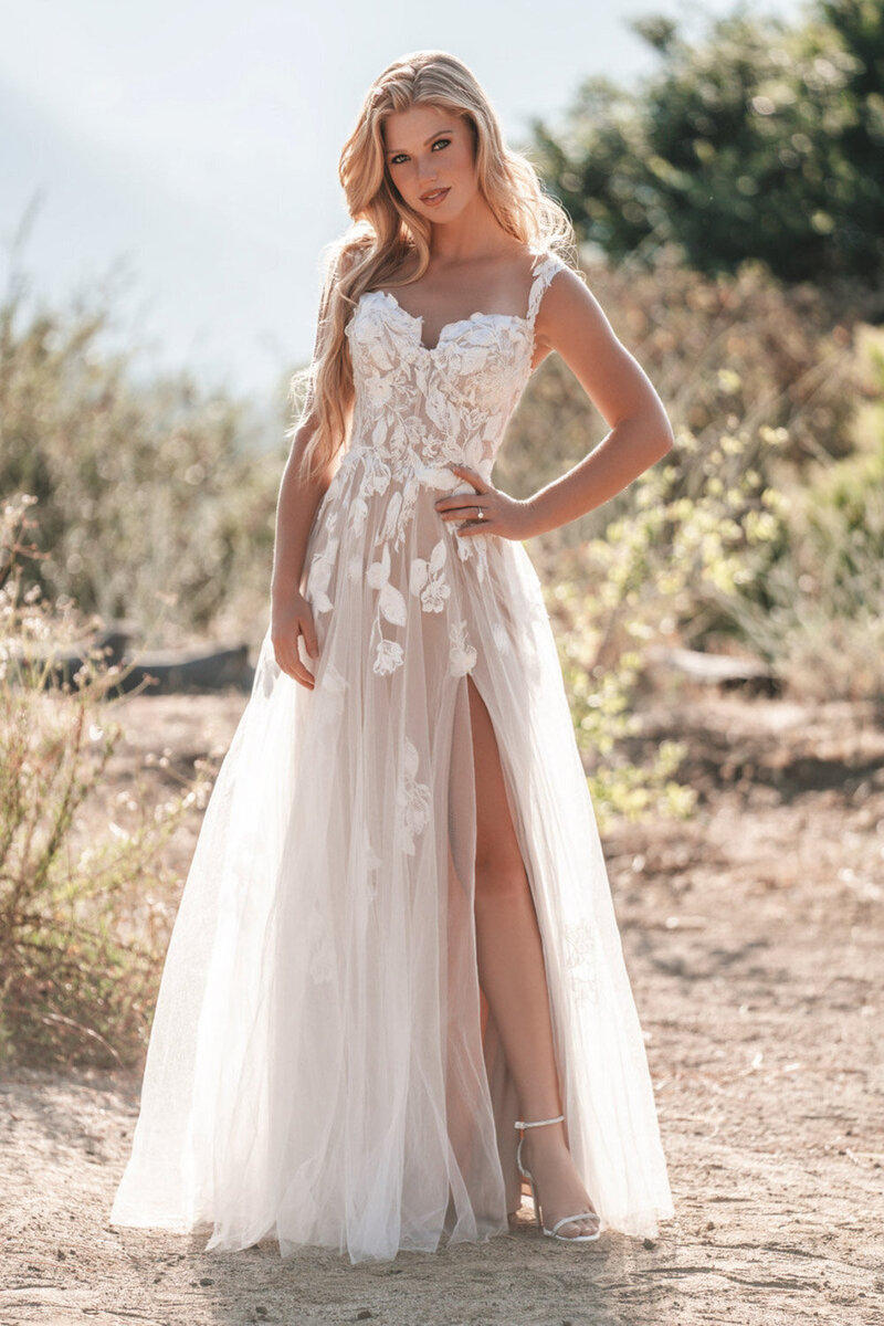 Woman wearing a lace wedding dress with a long slit in front doing a pose outdoors