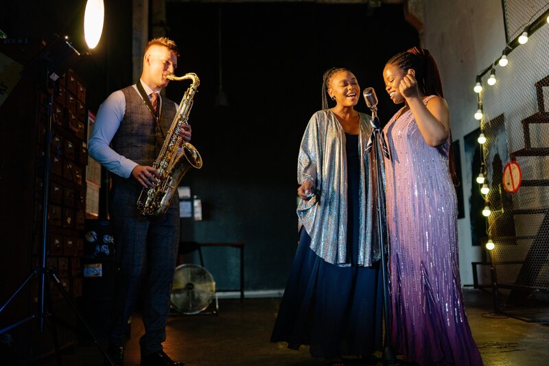 man playing a saxophone while two women sing