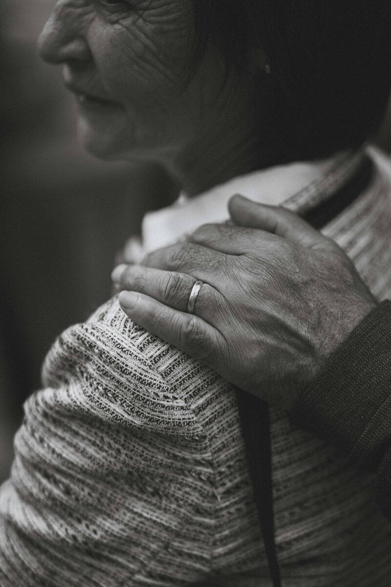 Black and white photo of hand on woman's shoulder