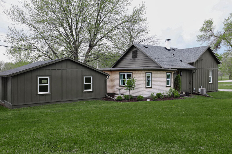 The exterior project by Nadine Stay. Board and batten siding install. Muddled Basil by Sherwin Williams exterior paint color. Flagstone path, brick front porch floor, and a custom built railing. Cabin exterior.