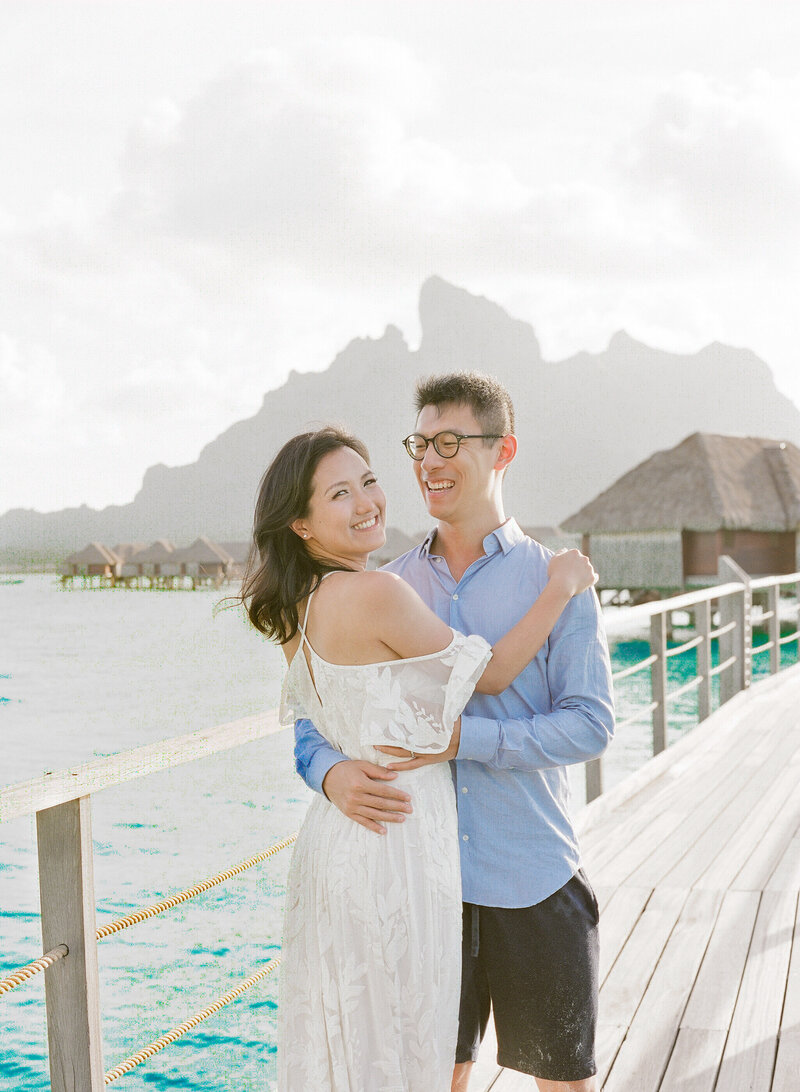 The couple smiling on desk in front mount otemanu in the Four Seasons Bora Bora