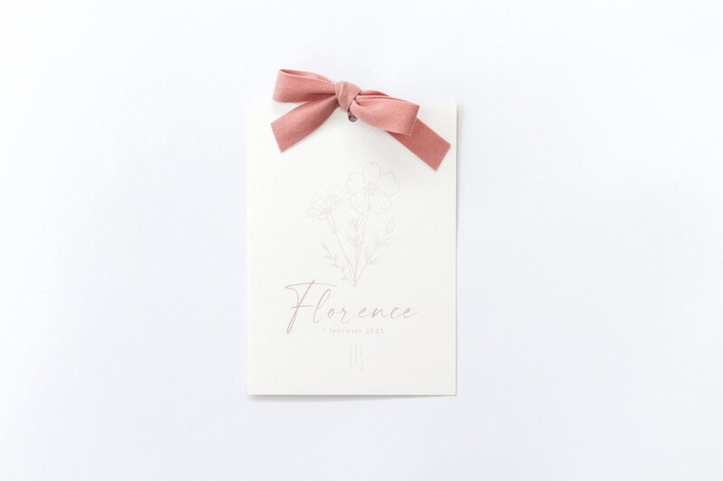 Geboortekaartje-met-stoffen-strik-en-geboortebloemen-illustratie