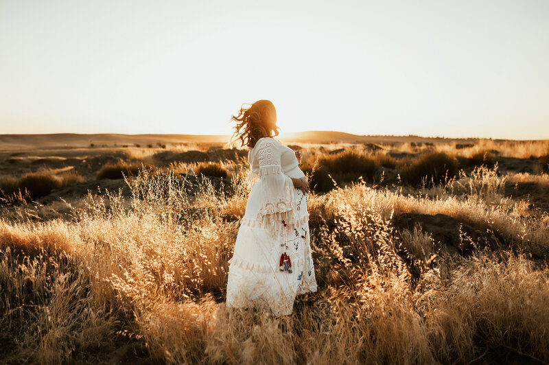 Pregnant mother dancing in a field at sunset.