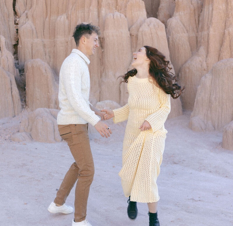 A couple laughing and dancing in front of rocks.