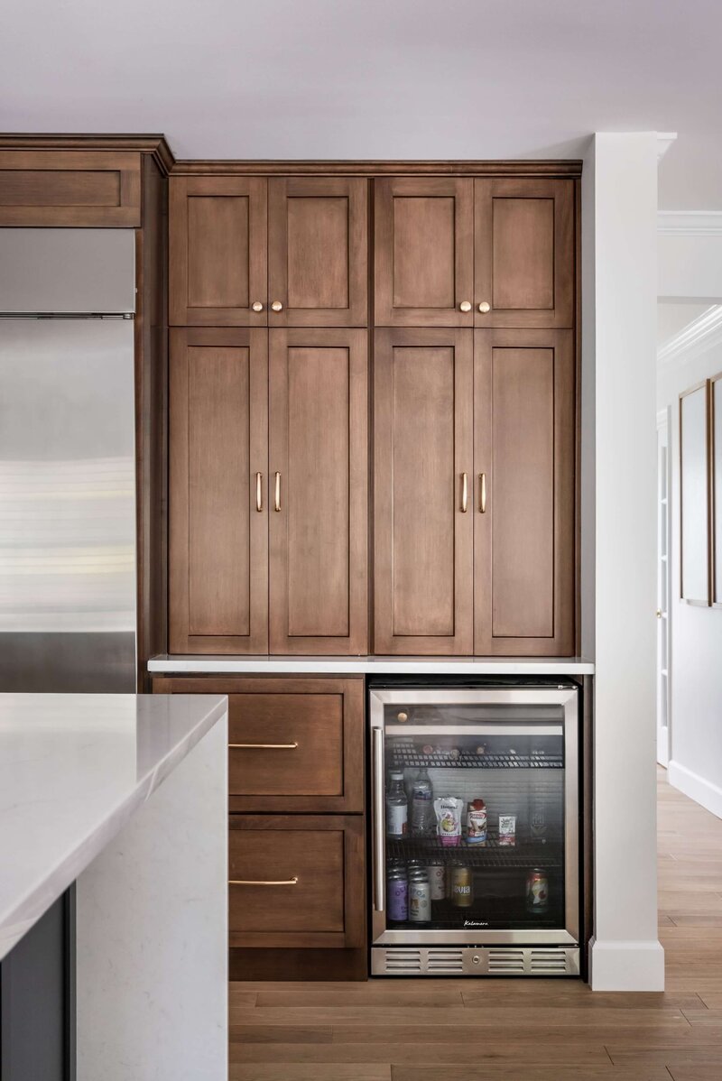 Kitchen remodel featuring warm wood cabinetry with brass hardware and a built-in beverage fridge.