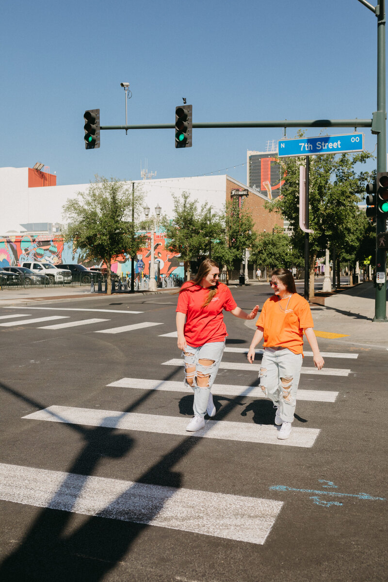 Two girls talk while crossing the street