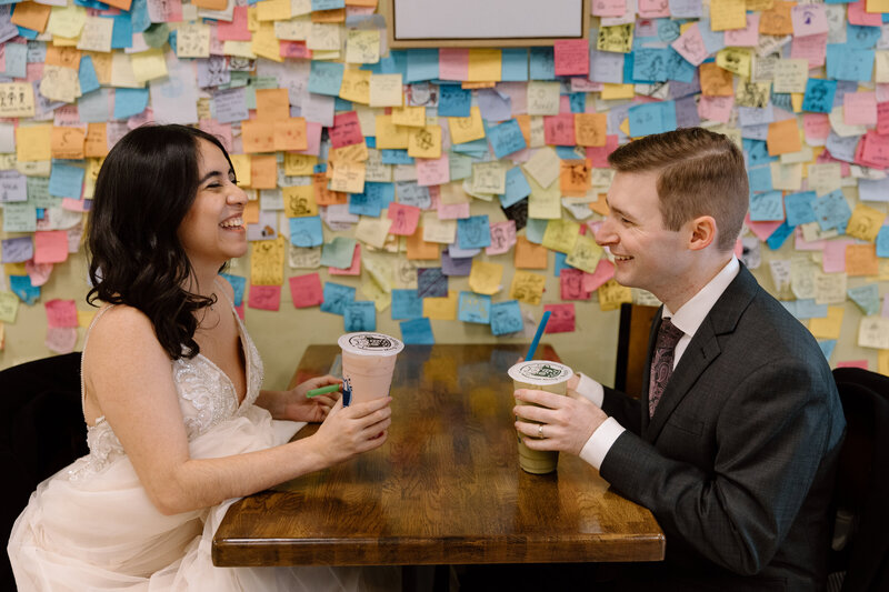 Eloping couple laughing and holding bubble tea.