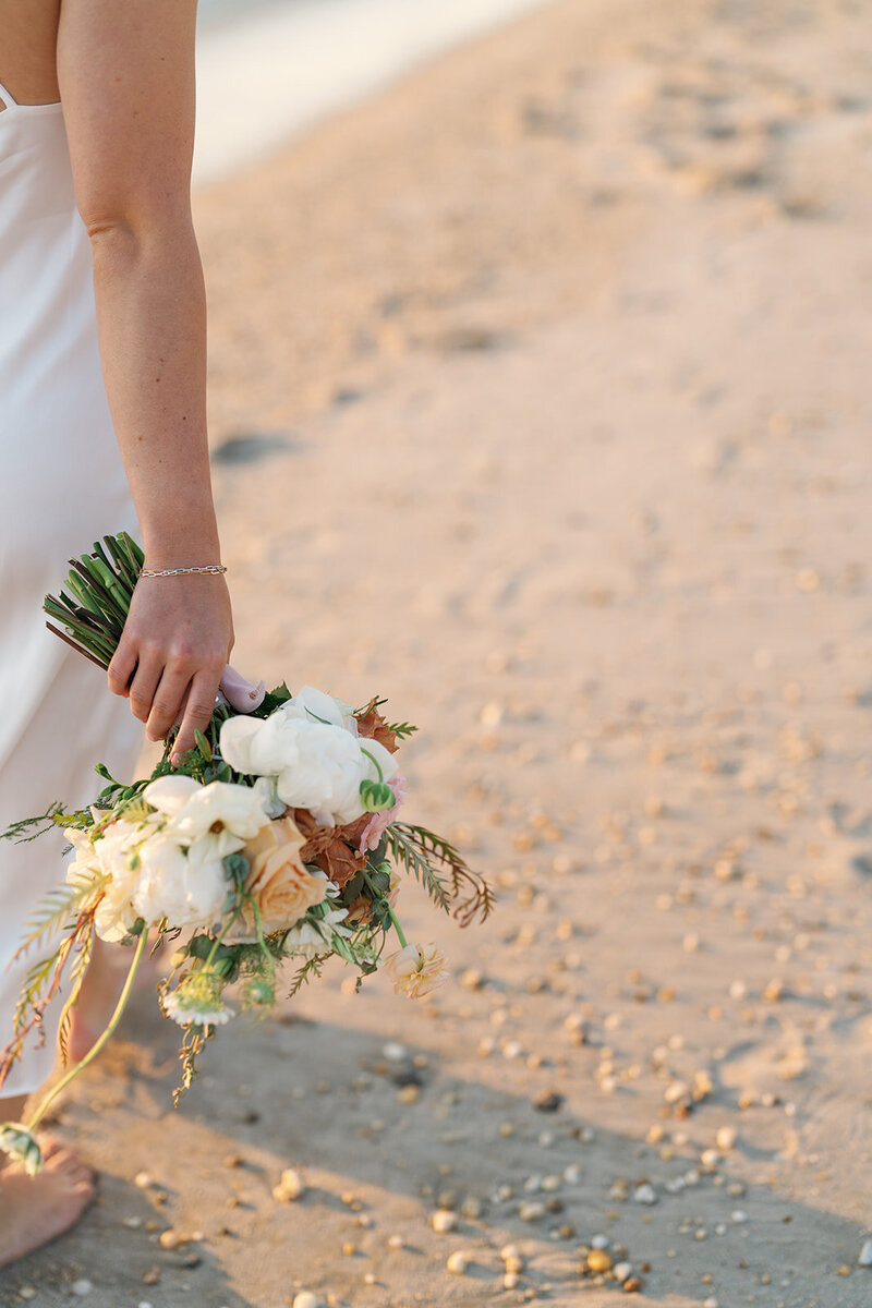Bride holding her bouquet on the beach