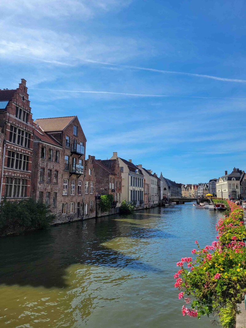 Historic canal lined with medieval brick buildings and colorful flowers in Ghent ©Stephanie Dosch | theViatrix Bespoke Belgium Itinerary