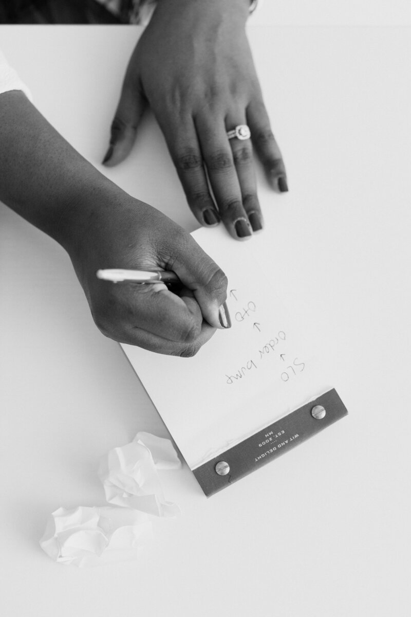 Black and white photo of hands writing on a notepad