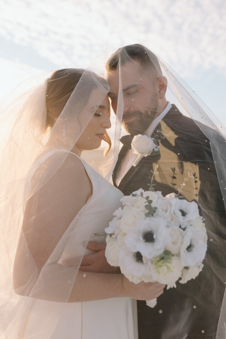 A romantic wedding couple resting their heads together.