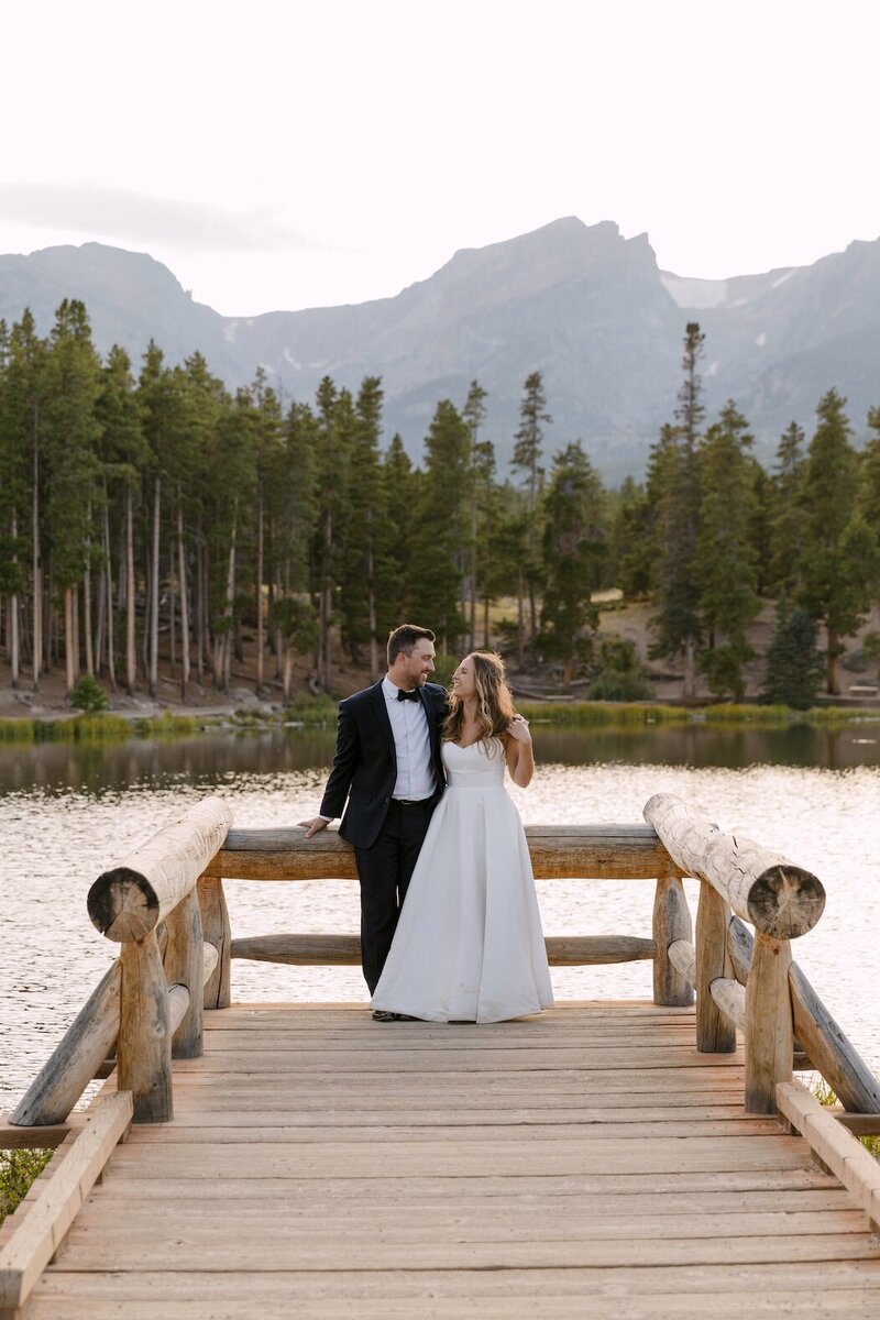 Bride and groom cuddling in front of the mountains at Sprague Lake for their wedding photos after their micro wedding ceremony in Estes Park 