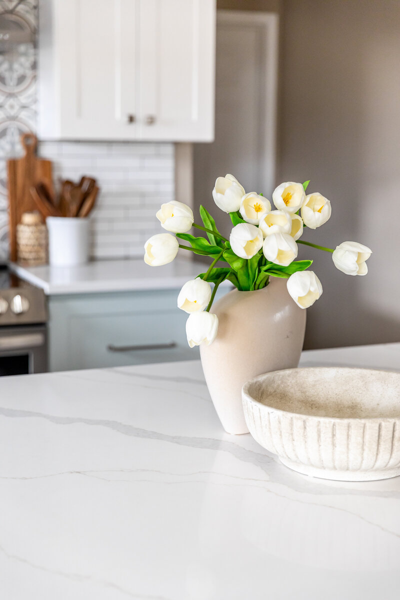 Kitchen island close-up photo with decorative bowls and vase with flowers.