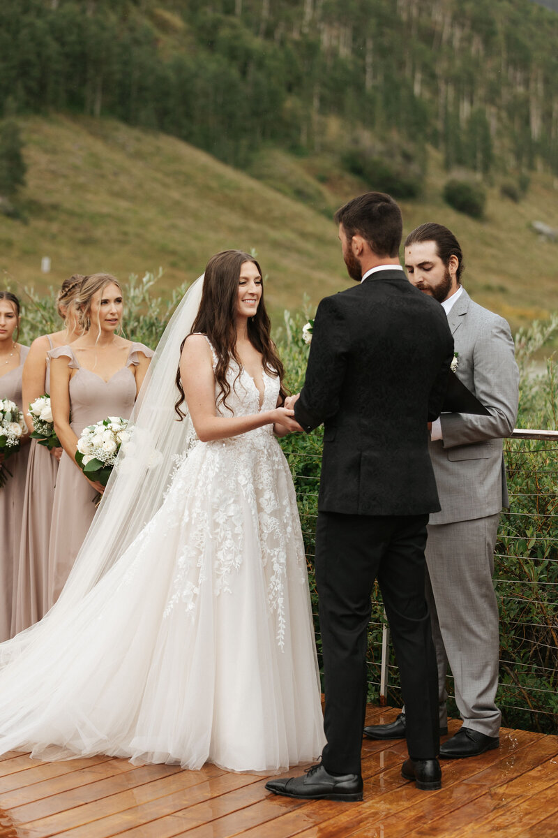 A newlywed couple standing on a mountain looking off in opposite directions.