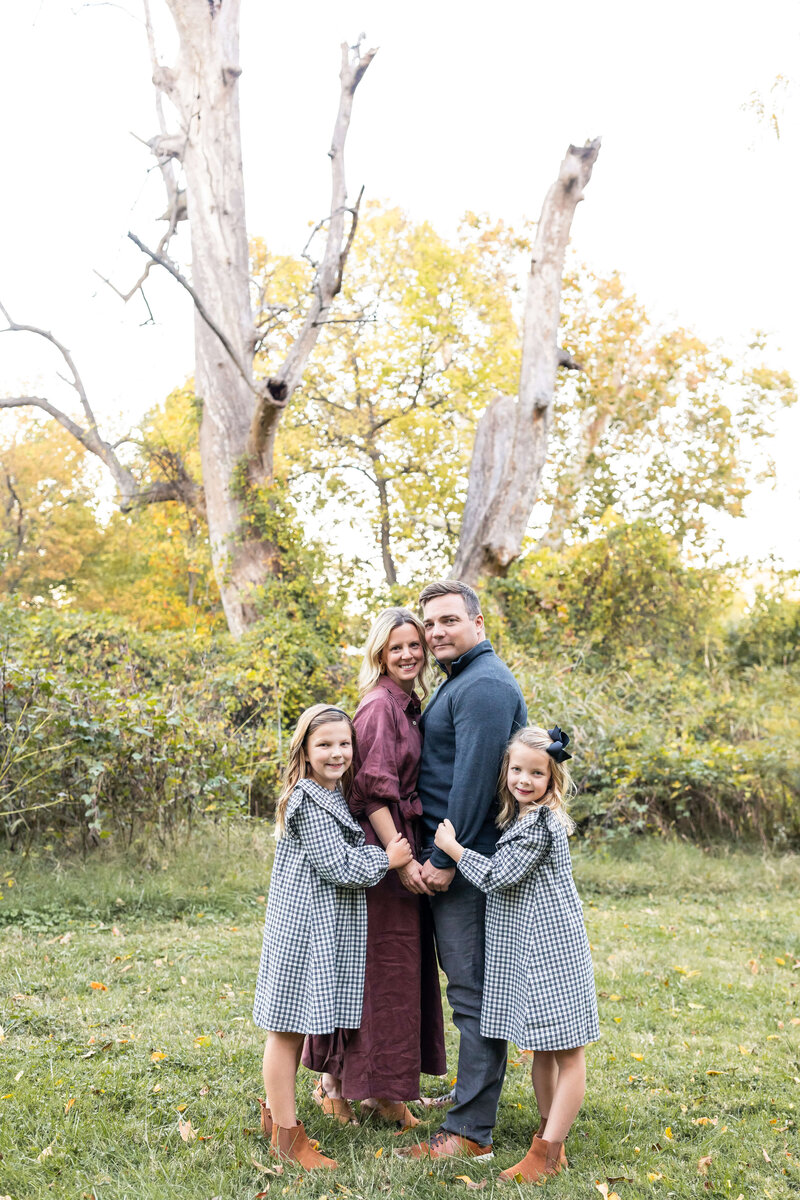 family of 4, 2 girls hugging mom and dad smiling