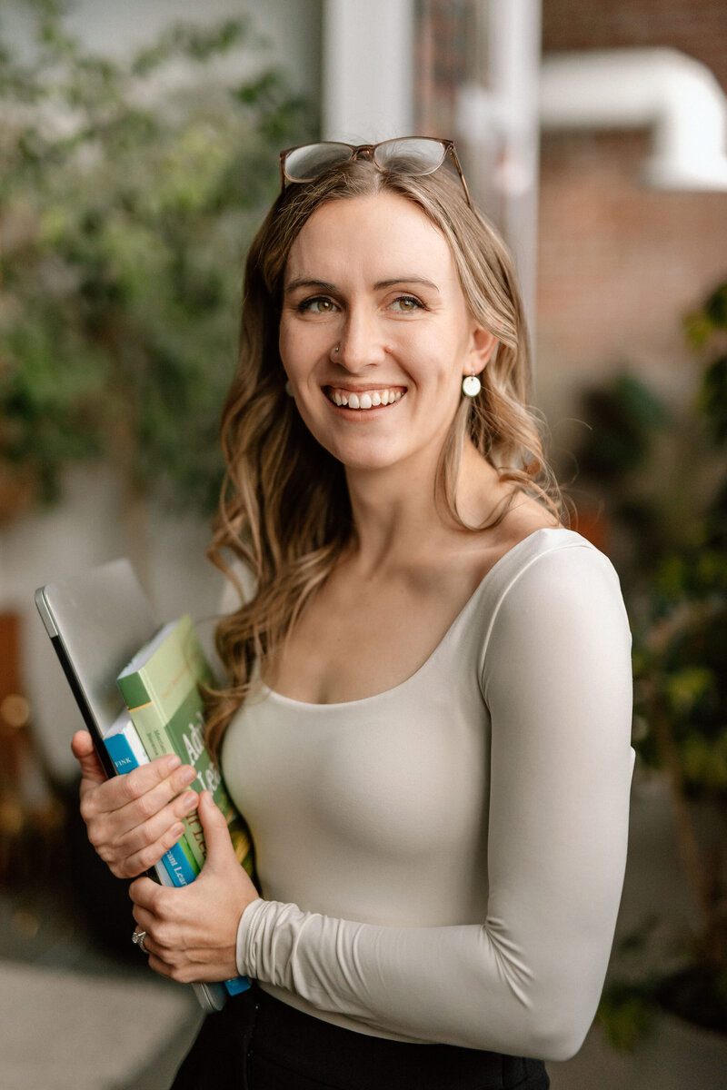 Online course creator Lauren of Entrepreneur, Academic holding learning materials ready to help a coach create the curriculum for their next online course launch.