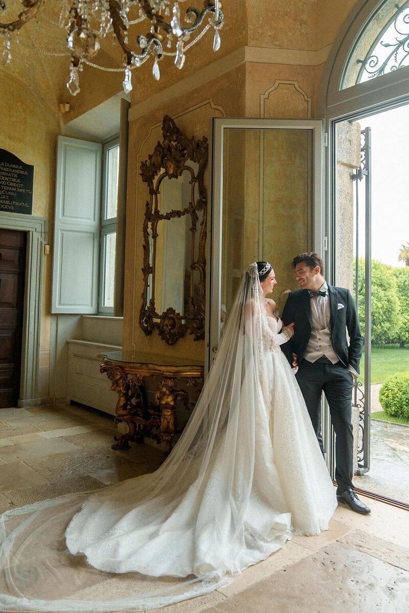 bride and groom standing in an open door way smiling at each other by San Diego wedding photography