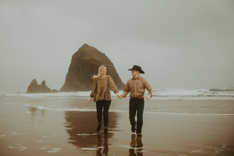 couple laughing holding hands in sand dunes