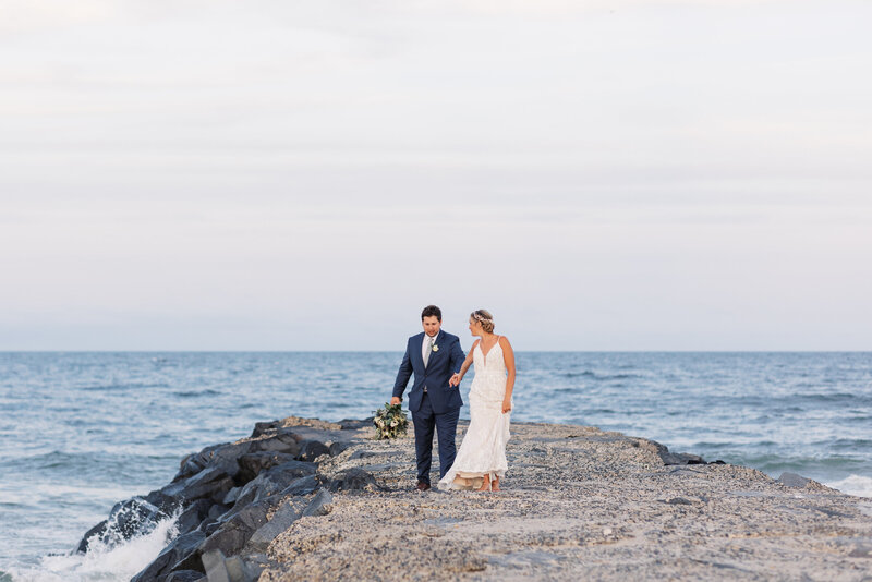 Bride and groom walk on the jetty during sunset portraits.