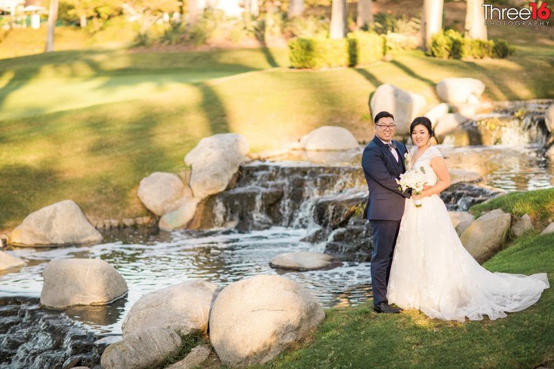 Bride and Groom pose for photos in front of the running water and small waterfalls at Tustin Ranch Golf Club