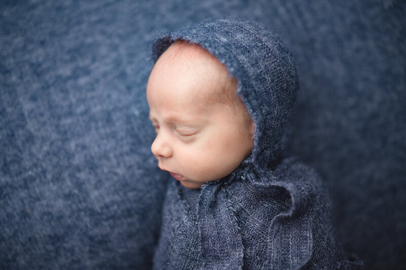 Newborn wrapped in blue blanket sleeping