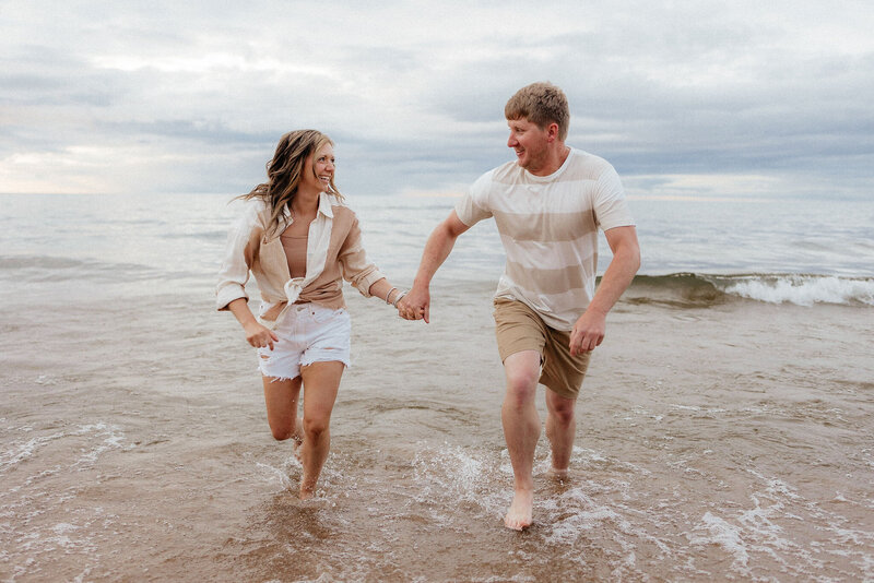 couple running on the beach at their Lake Michigan engagement photoshoot