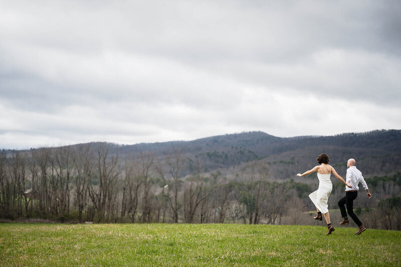 A couple frolics together hand-in-hand at Heritage Park in Blacksburg, Virginia on their elopement day.