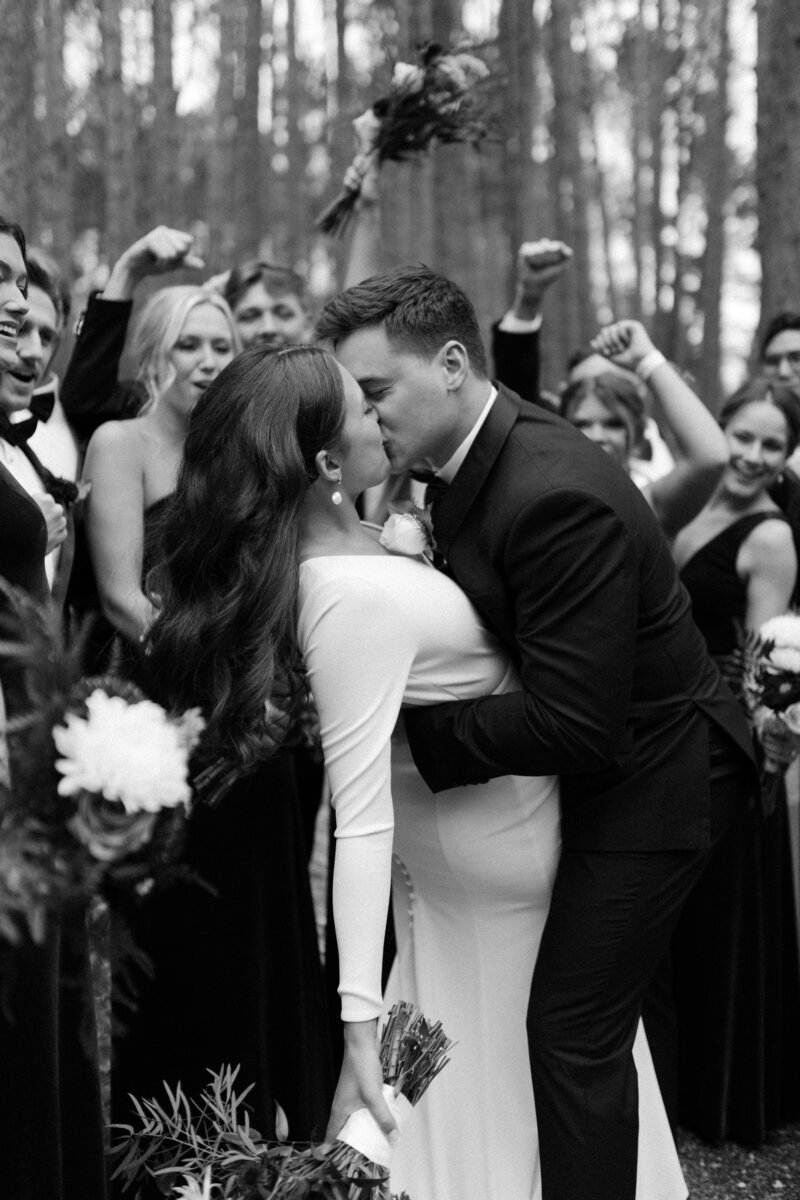 Bride and groom share a kiss while their wedding party surrounds them with applause during a Minneapolis wedding.