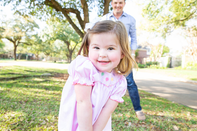 Toddler in a pink dress smiles at the camera