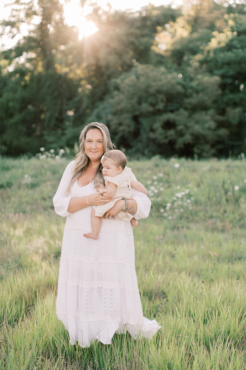Woman smiles and holds baby in Mechanicsburg field.