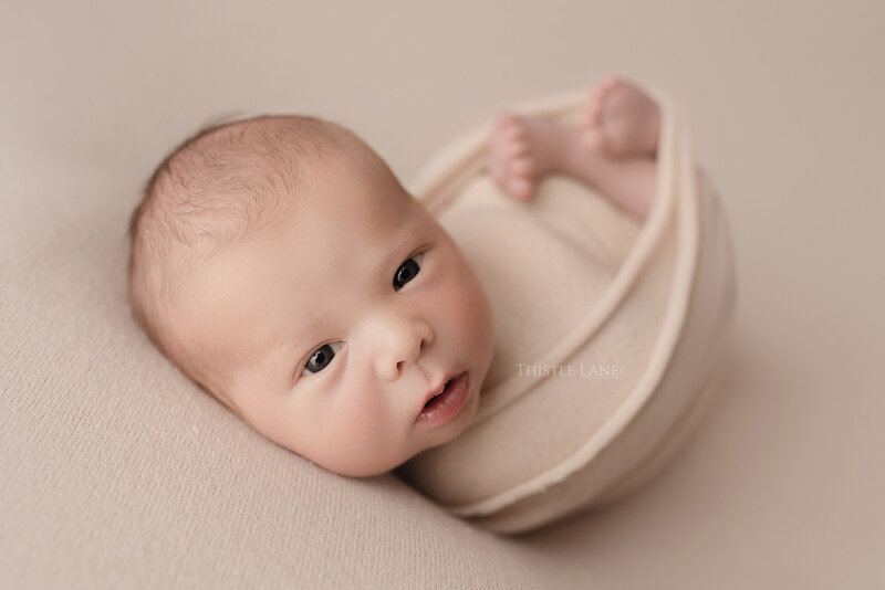 Newborn baby boy in huck finn wrapped pose
