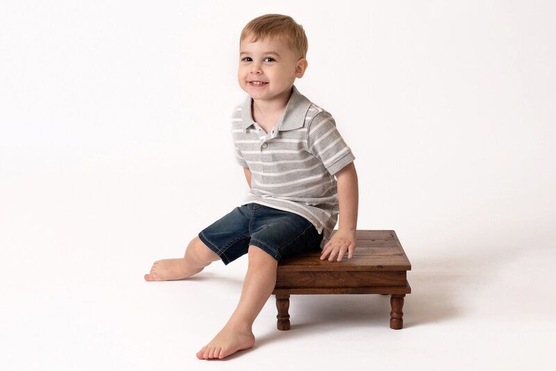 Grinning toddler boy sitting on small stool