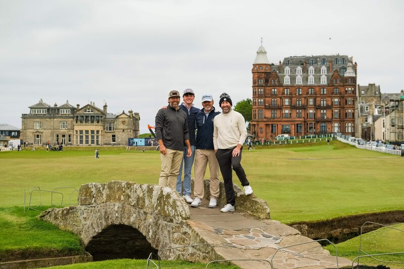 Guys standing on an old stone bridge with old buildings behind them