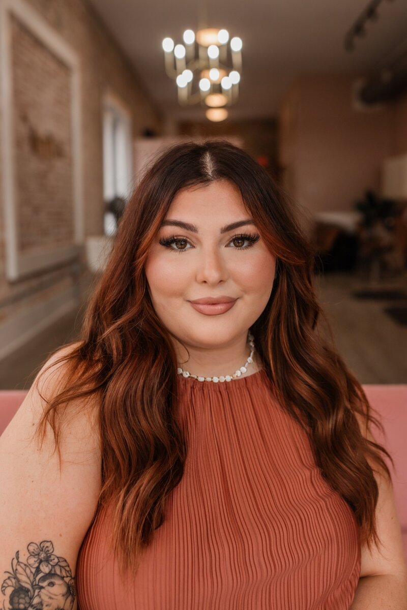 Hairstylist with warm brunette waves at The Vanity Hair Studio in Griffin, GA, offering hair color transformations, including highlights and balayage.