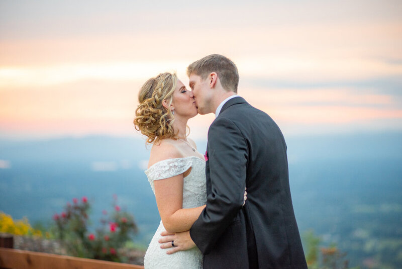 A close up of a of a bride and groom kissing with a stunning view of the Blue Ridge Mountains behind them.