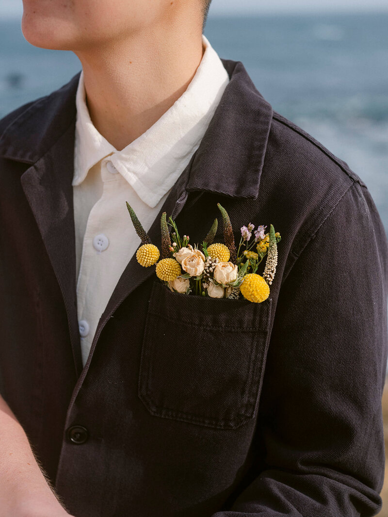 detail of dried flowers in heart pocket of the bride