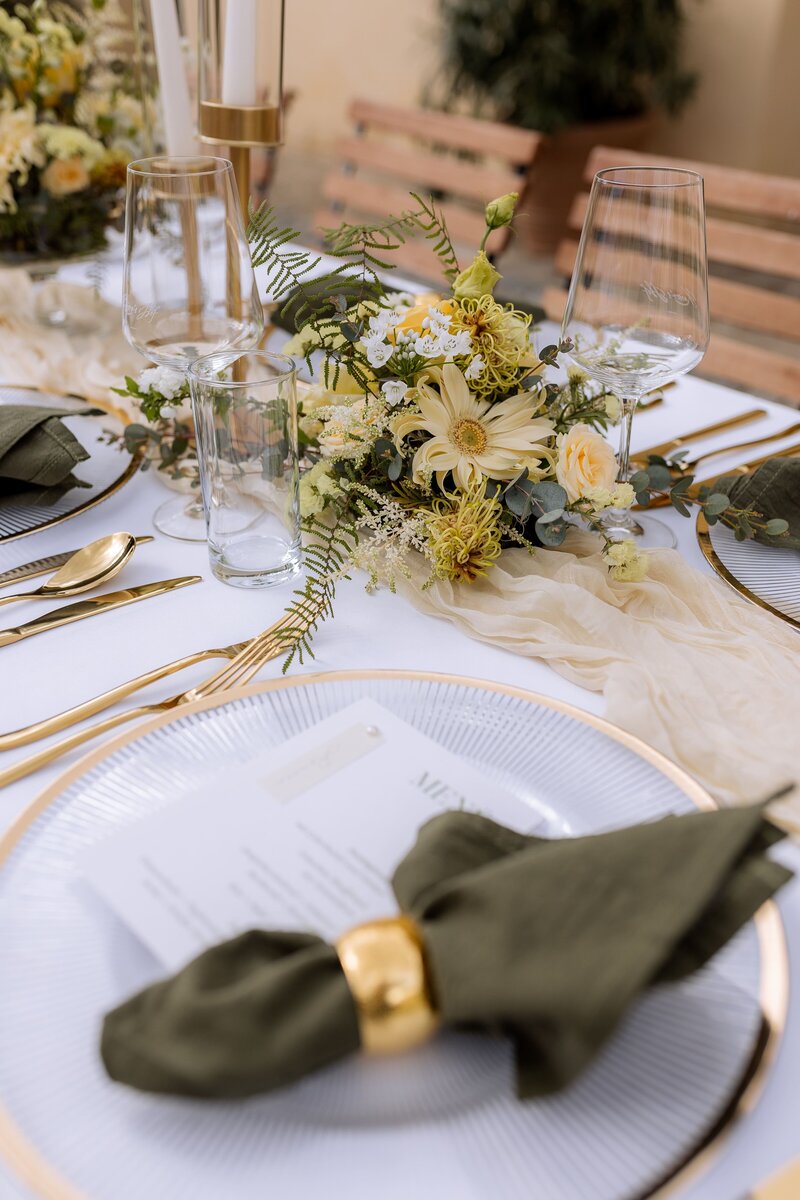 Detailfoto von gedecktem Tisch mit gelben Blumen und gruener Serviette