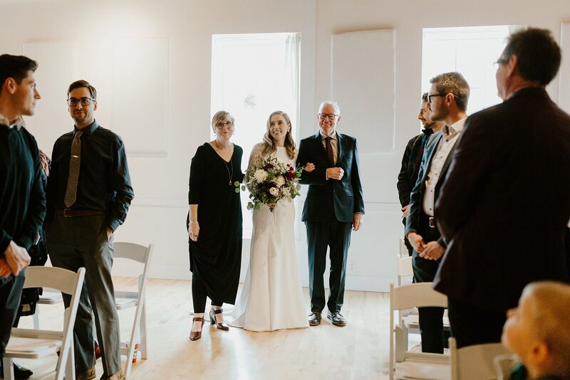 Bride being escorted down the aisle by her parents at an Alberta wedding.