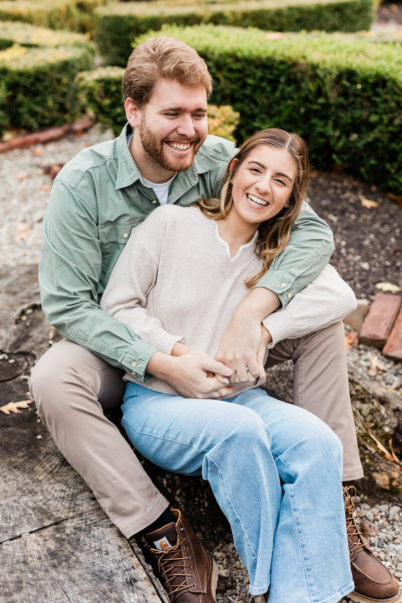 Couple snuggling while sitting on stone step, giggling