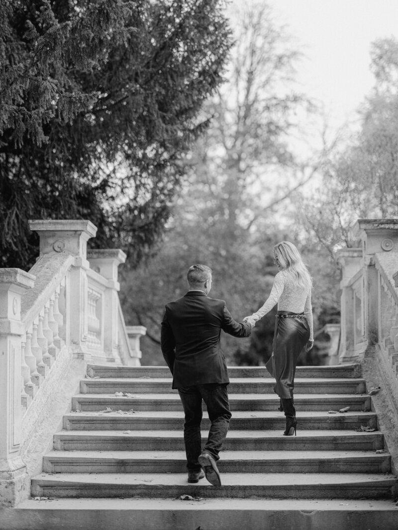 a black and white photos of a couple walking up the stairs of a bridge in Paris