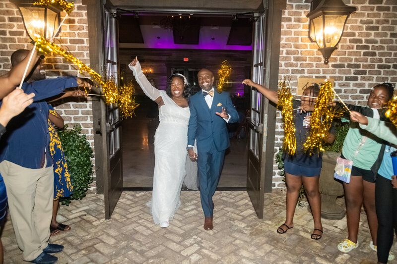 A bride and groom exit their reception with pom poms