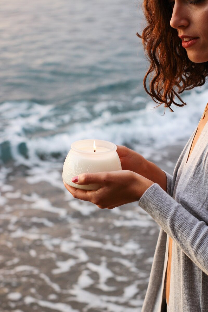 Woman holding a candle next to the shore