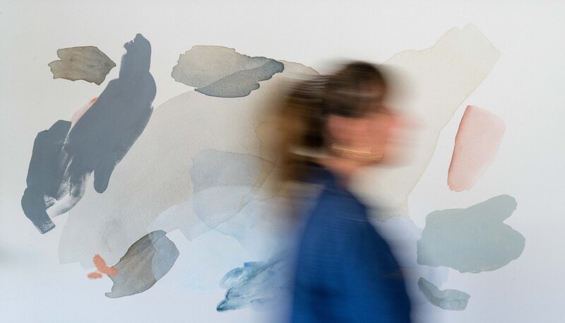 personal branding photo of an artist in front of their abstract painting with their face blurred out