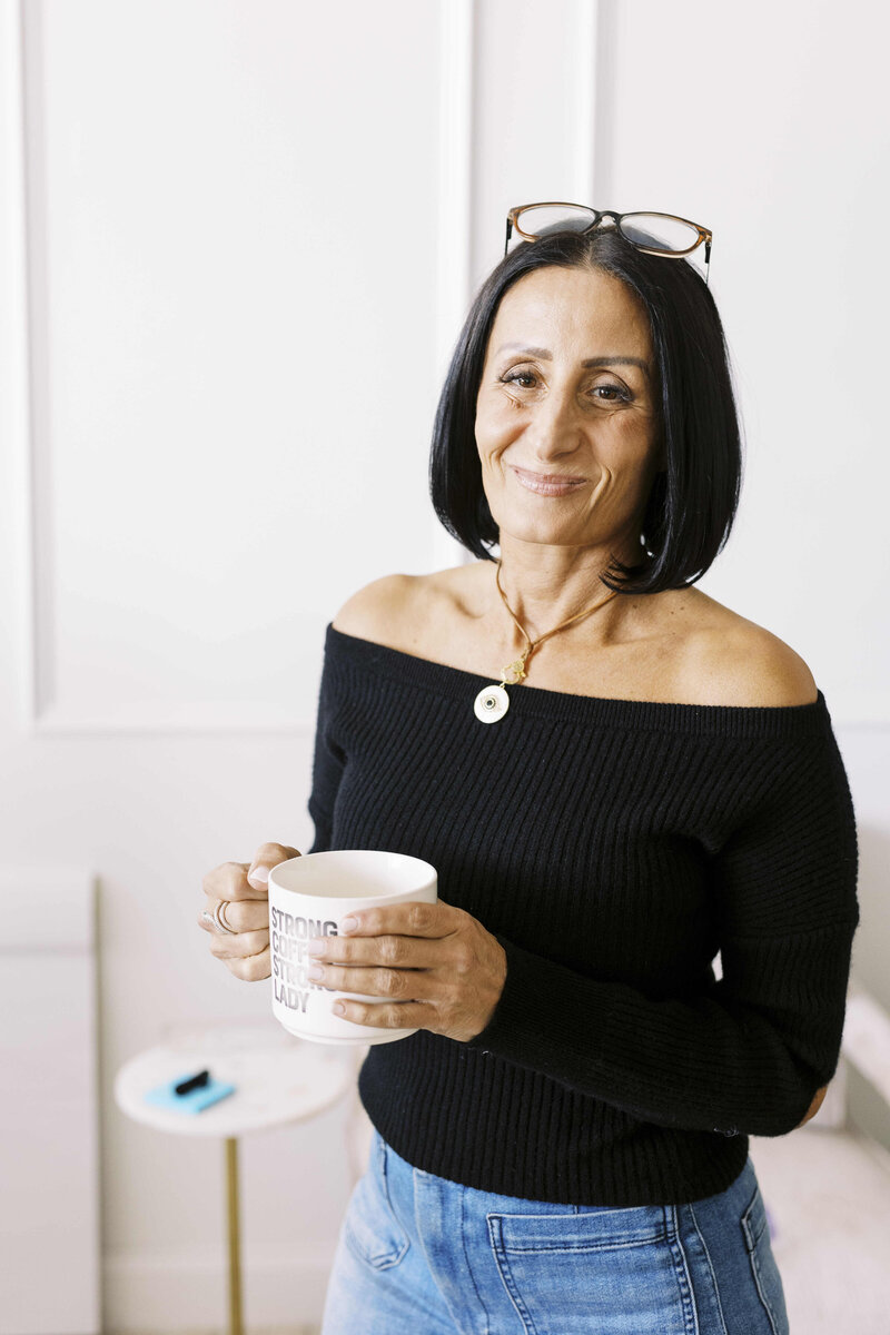 Tarah smiling and holding cup of coffee