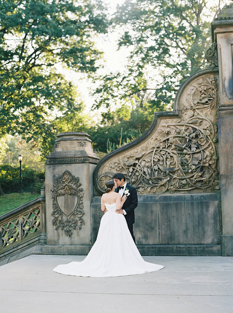 The back of the bride's dress as the groom gives her a kiss on the stairs of Bethesda Terrace. Beautiful sunrise editorial session.