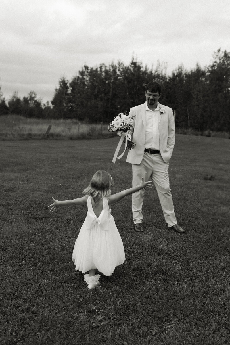 Flower girl runs with open arms to her dad on his wedding day.