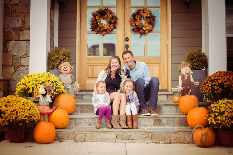 Beautiful front porch Family Portrait decorated with Orange Pumpkins and yellow Mums for Fall. Photo taken by Lydia Teague Photography based in Dripping Springs Texas.