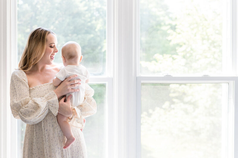 mom holding baby by window photographed by NPS Photography