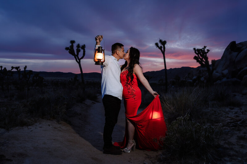 Joshua Tree Elopement with Asian couple during sunset blue hour at Hidden Valley holding lanterns and kissing.