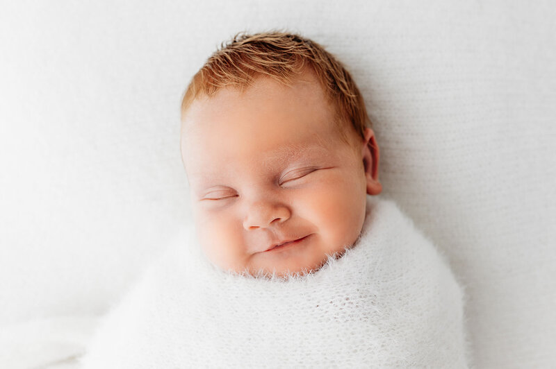 newborn baby girl swaddled smiling